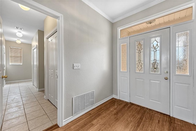 foyer entrance with light wood-style floors, baseboards, visible vents, and crown molding