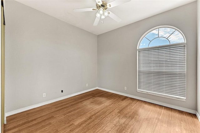 empty room with ceiling fan, light wood finished floors, and baseboards