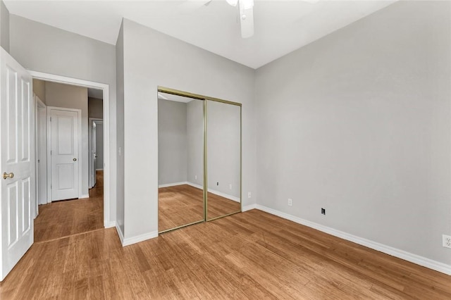 unfurnished bedroom with a closet, wood finished floors, a ceiling fan, and baseboards