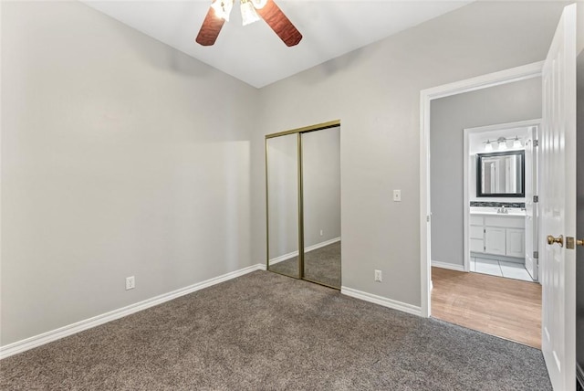 unfurnished bedroom featuring carpet floors, a closet, a ceiling fan, a sink, and baseboards