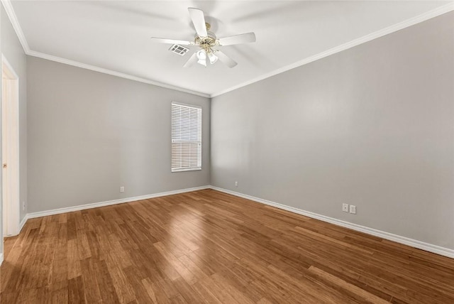 spare room featuring visible vents, ornamental molding, ceiling fan, wood finished floors, and baseboards