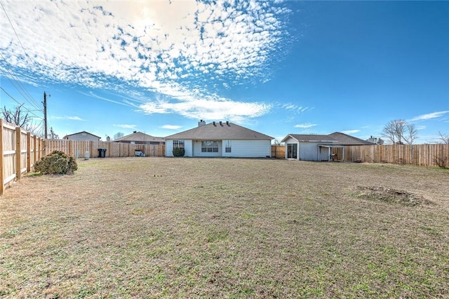 rear view of property featuring a lawn and a fenced backyard