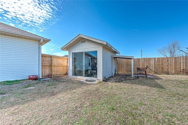 back of house featuring a fenced backyard, a lawn, and an outbuilding