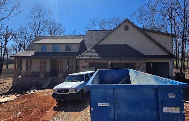 view of front of home featuring a garage and a shingled roof