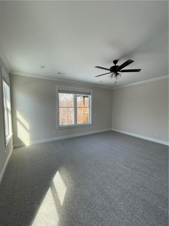 carpeted empty room featuring ceiling fan, ornamental molding, and baseboards