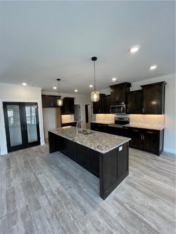 kitchen with tasteful backsplash, a large island, appliances with stainless steel finishes, light stone countertops, and a sink