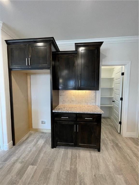 kitchen featuring ornamental molding, backsplash, light wood-style flooring, and light stone countertops