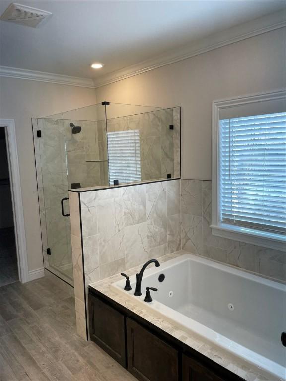 bathroom with a stall shower, visible vents, ornamental molding, wood finished floors, and a whirlpool tub