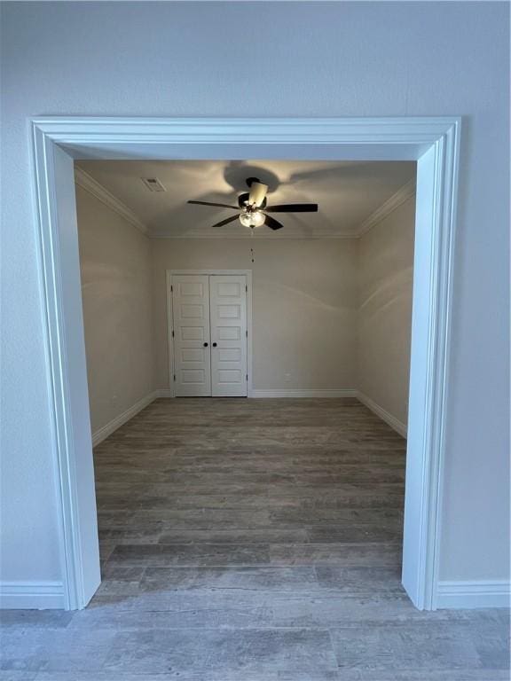 empty room with visible vents, a ceiling fan, crown molding, and wood finished floors