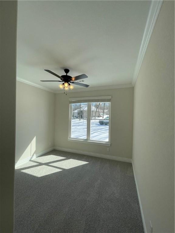 carpeted spare room with baseboards, ceiling fan, and crown molding