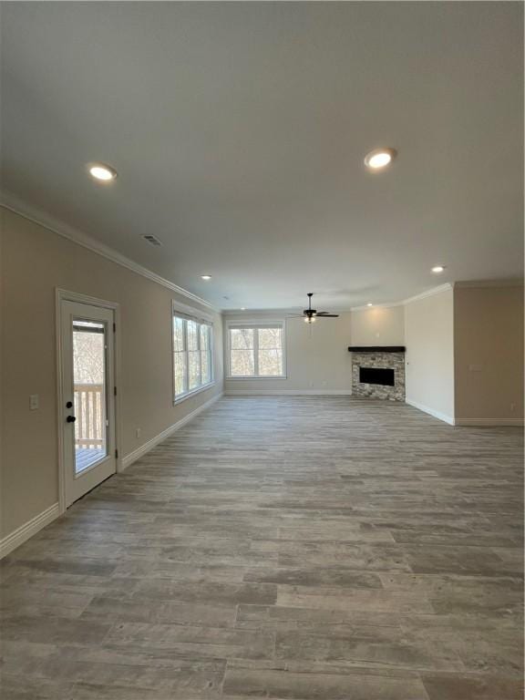 unfurnished living room with ornamental molding, a fireplace, baseboards, and wood finished floors