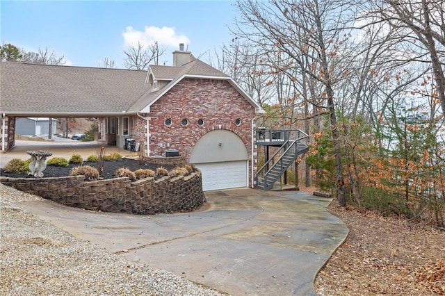 view of front of property with a garage, brick siding, stairs, roof with shingles, and a chimney