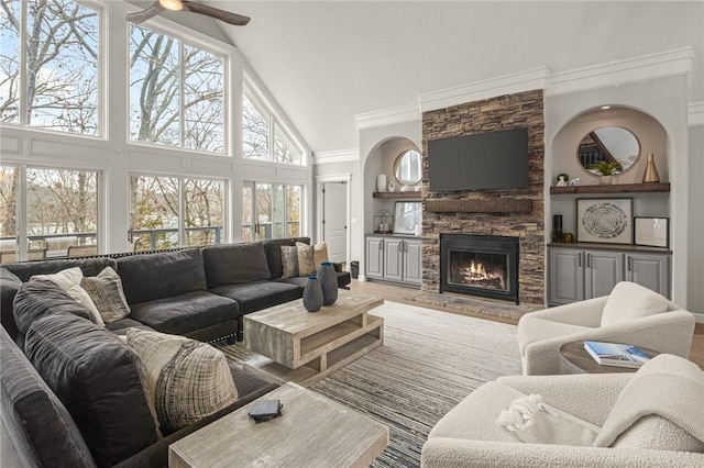 living area with ornamental molding, ceiling fan, high vaulted ceiling, and a fireplace