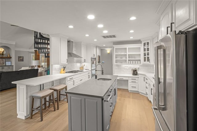 kitchen featuring wall chimney exhaust hood, white cabinetry, stainless steel appliances, and a sink