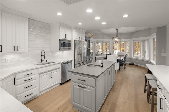 kitchen featuring white cabinetry, appliances with stainless steel finishes, light wood-style flooring, and a sink