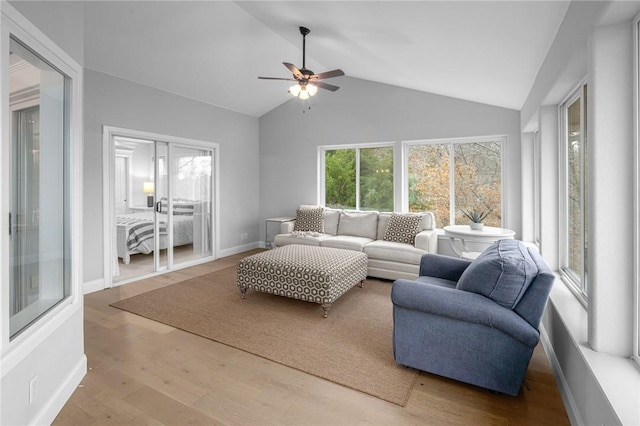 living area with lofted ceiling, ceiling fan, wood finished floors, and baseboards