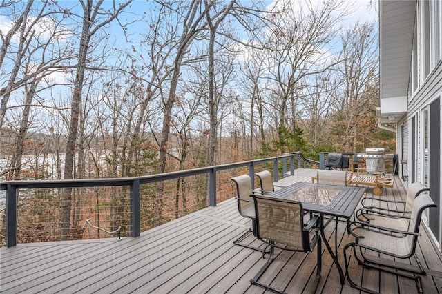 wooden terrace featuring outdoor dining space and area for grilling