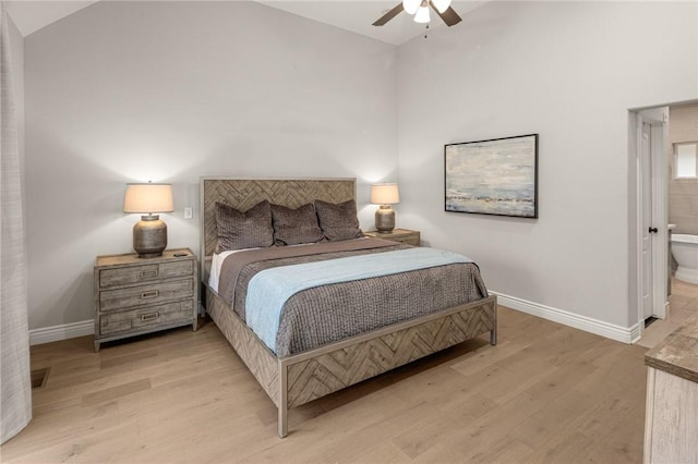 bedroom featuring lofted ceiling, light wood-style floors, ensuite bath, and baseboards