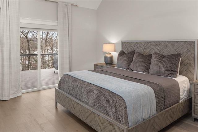 bedroom featuring vaulted ceiling, wood finished floors, and access to exterior