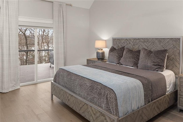 bedroom featuring lofted ceiling, wood finished floors, and access to exterior