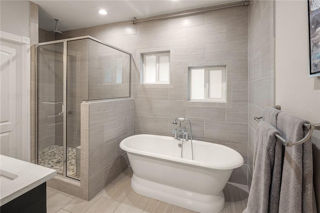 full bathroom featuring tile patterned floors, vanity, a freestanding tub, a shower stall, and recessed lighting