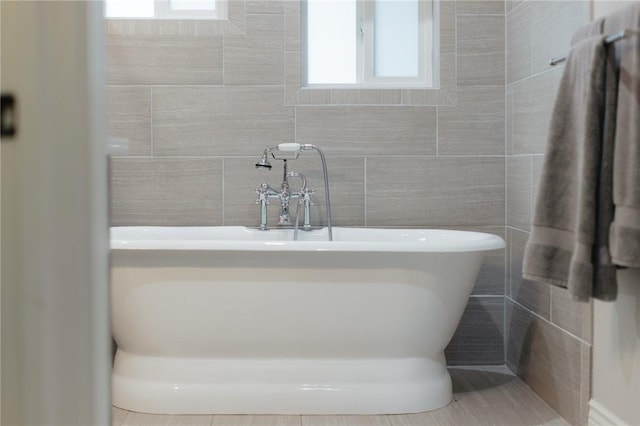 bathroom featuring a freestanding tub and tile walls