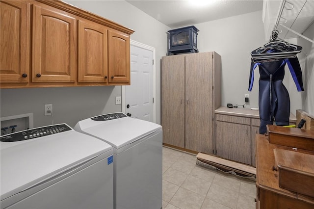 laundry room featuring washing machine and clothes dryer, light tile patterned floors, and cabinet space