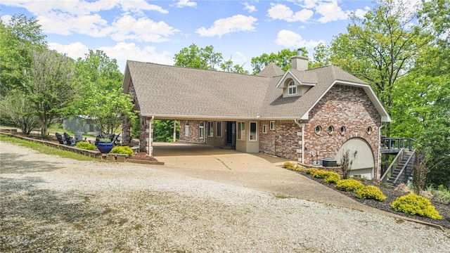 view of front of house featuring driveway, a chimney, roof with shingles, stairway, and an attached carport