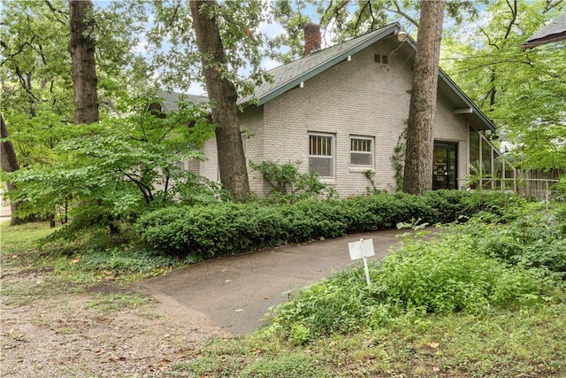 view of side of property featuring a chimney and brick siding