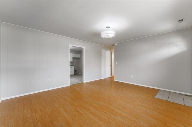 empty room featuring light wood finished floors, baseboards, and visible vents