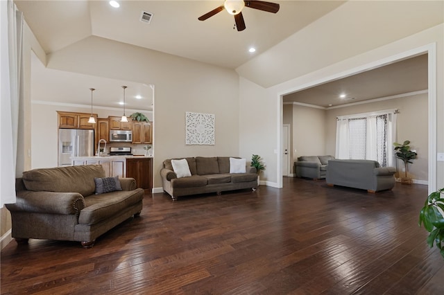 living area featuring lofted ceiling, visible vents, ceiling fan, and dark wood finished floors
