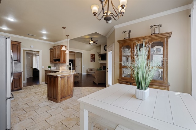 kitchen with freestanding refrigerator, crown molding, pendant lighting, open floor plan, and ceiling fan with notable chandelier
