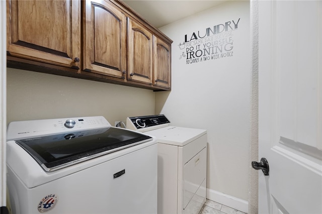 clothes washing area featuring washing machine and dryer, baseboards, cabinet space, and light tile patterned floors