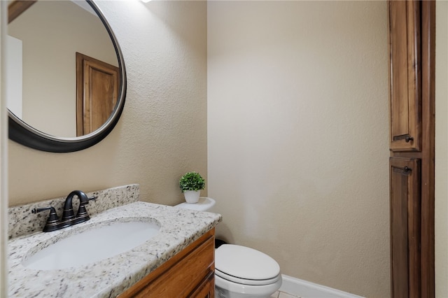 half bathroom featuring toilet, vanity, and baseboards