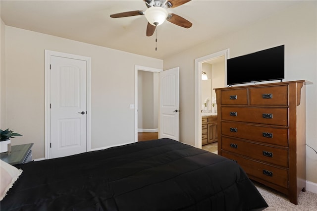 bedroom featuring ensuite bath, a ceiling fan, baseboards, and light carpet