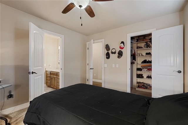 bedroom featuring ensuite bath, baseboards, and ceiling fan