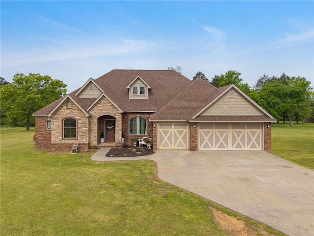 view of front of property featuring driveway, stone siding, roof with shingles, a front yard, and a garage