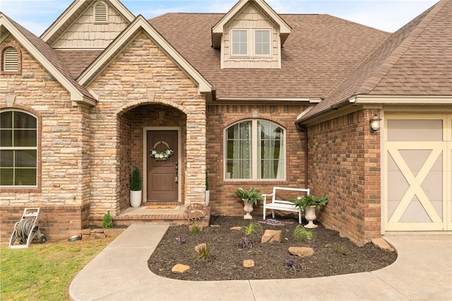 view of exterior entry featuring brick siding, roof with shingles, stone siding, and a garage