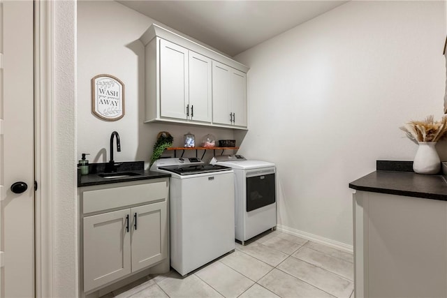 laundry area featuring light tile patterned floors, washing machine and dryer, a sink, baseboards, and cabinet space