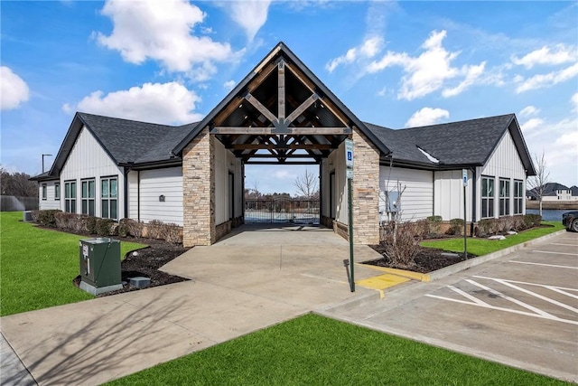 view of front of house with board and batten siding, concrete driveway, a shingled roof, and a front lawn