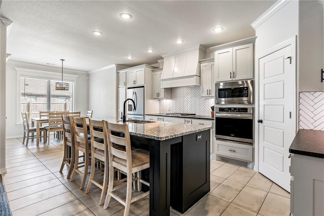 kitchen featuring stainless steel appliances, tasteful backsplash, custom range hood, ornamental molding, and a kitchen breakfast bar