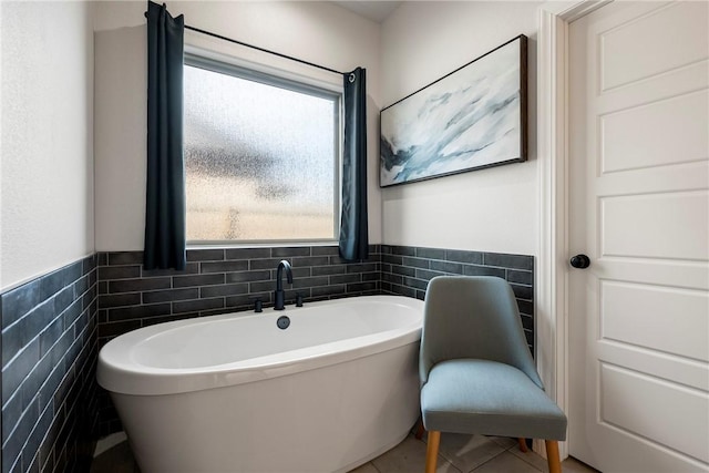 full bath featuring a wainscoted wall, a soaking tub, tile walls, and tile patterned floors