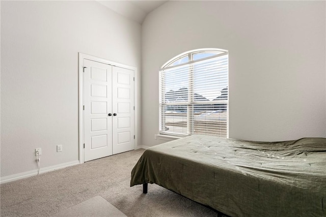 bedroom with a closet, carpet flooring, vaulted ceiling, and baseboards