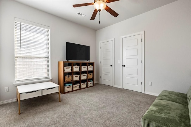 sitting room with carpet floors, visible vents, baseboards, and a ceiling fan