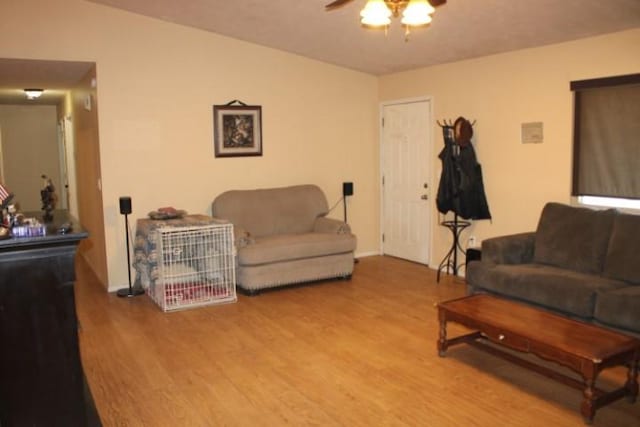 living area with ceiling fan, baseboards, and wood finished floors