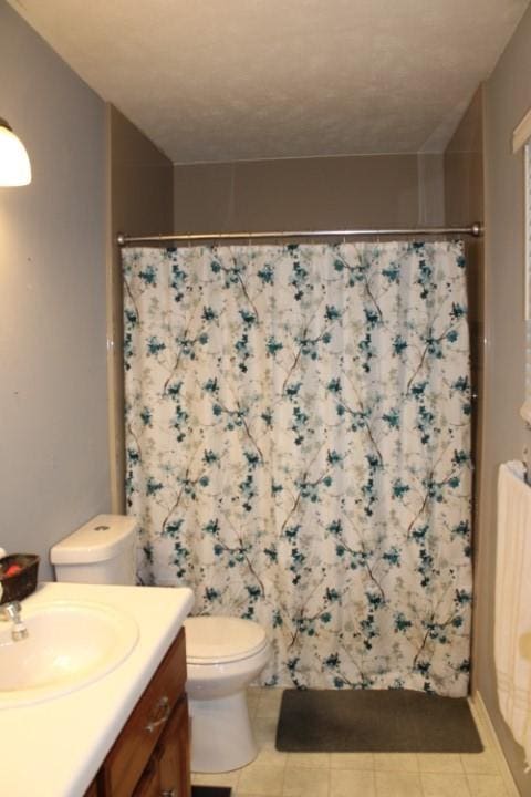 bathroom featuring toilet, curtained shower, tile patterned flooring, and vanity