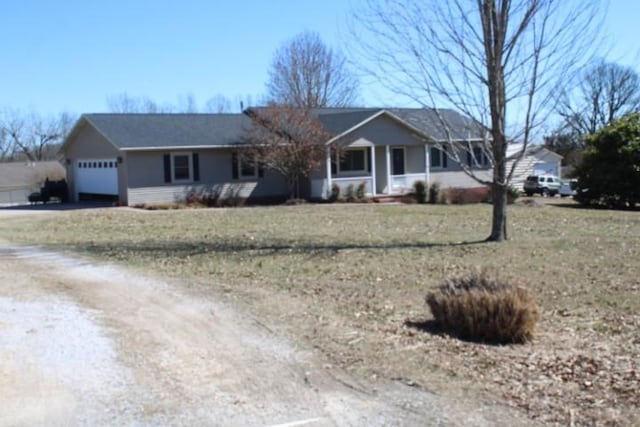 ranch-style house with driveway, an attached garage, and a front lawn