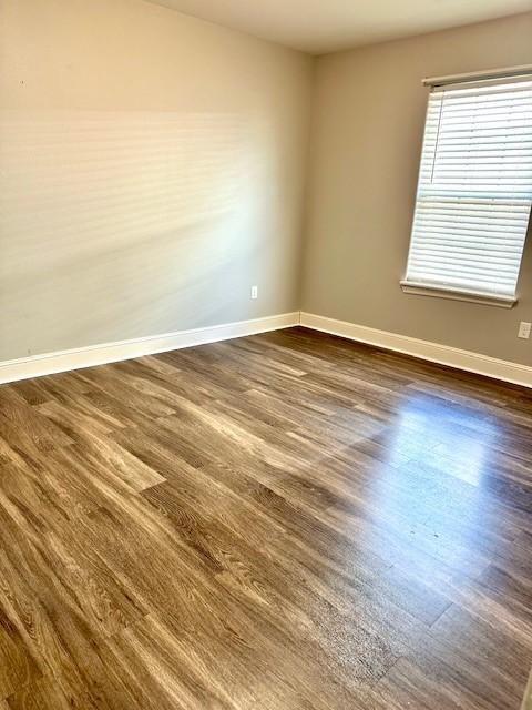 unfurnished room with dark wood-style floors and baseboards