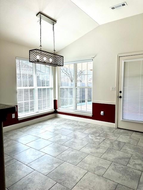 unfurnished dining area with lofted ceiling, visible vents, and baseboards