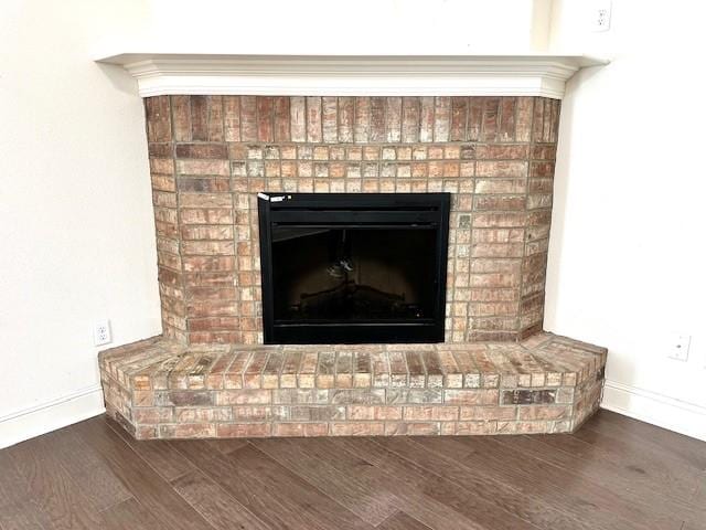 room details featuring a fireplace, baseboards, and wood finished floors